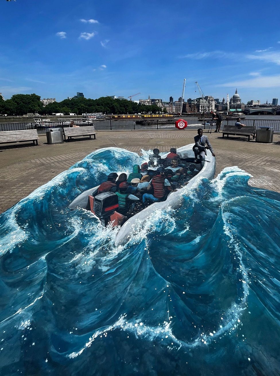 Eskander Turki kneeling next to 3D artwork created by street artists 3D Joe & Max on London's Southbank.