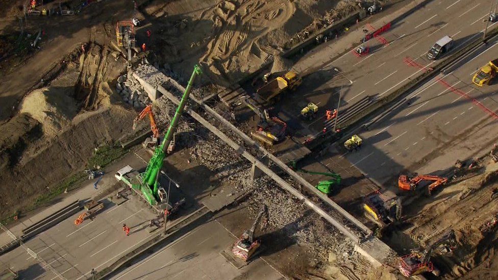 Cranes and vehicles surround a bridge that is being taken down