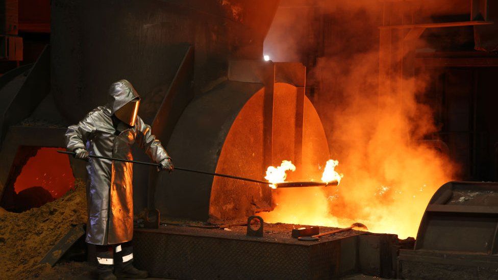 A worker takes a sample of molten iron flowing from steelworks in Duisburg, Germany.
