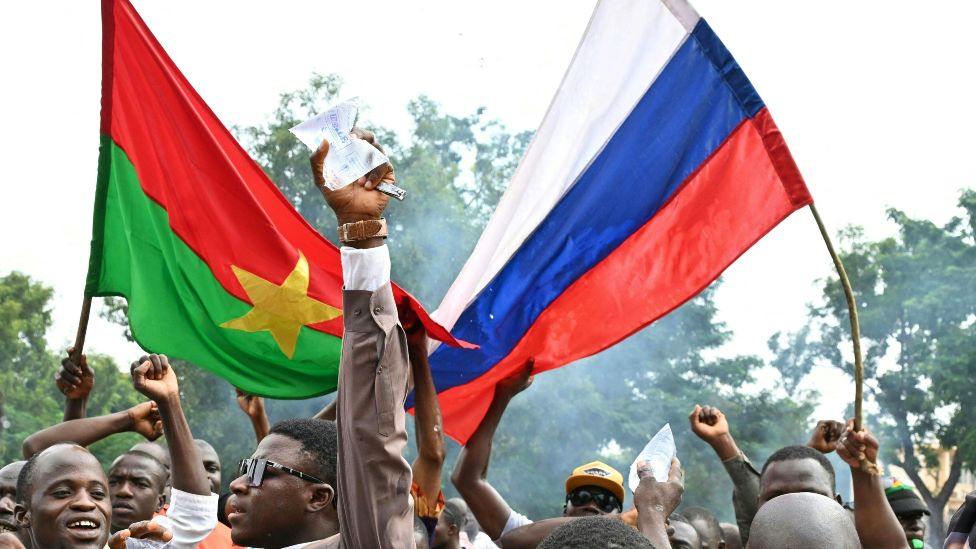Supporters of Burkina Faso's new junta leader Ibrahim Traoré hold national flags of Burkina Faso and Russia during a demonstration near the national radio and television headquarters (RTB) in Ouagadougou on 6 October 2022