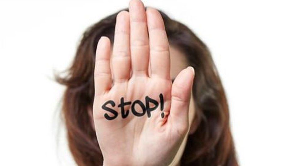 Woman holding up her hand with 'stop' written on her palm