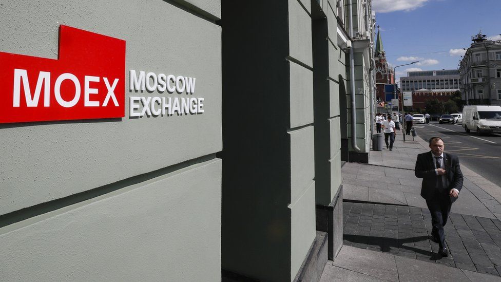 A man walks near a building with the logo of the Moscow Exchange in Russia.