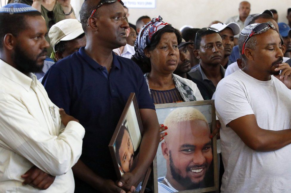 Relatives hold pictures of Solomon Tekah at his funeral in Haifa on 2 July 2019