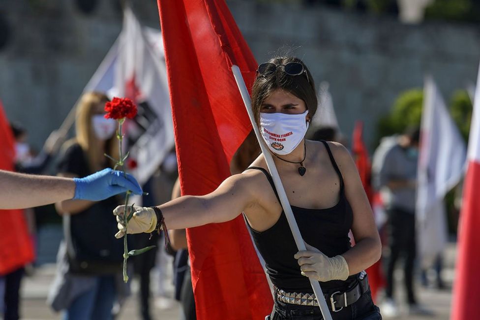 A woman hands out red carnations