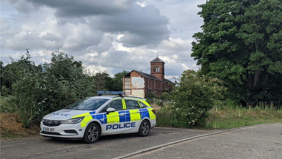A police car with a disused Victorian building in the background