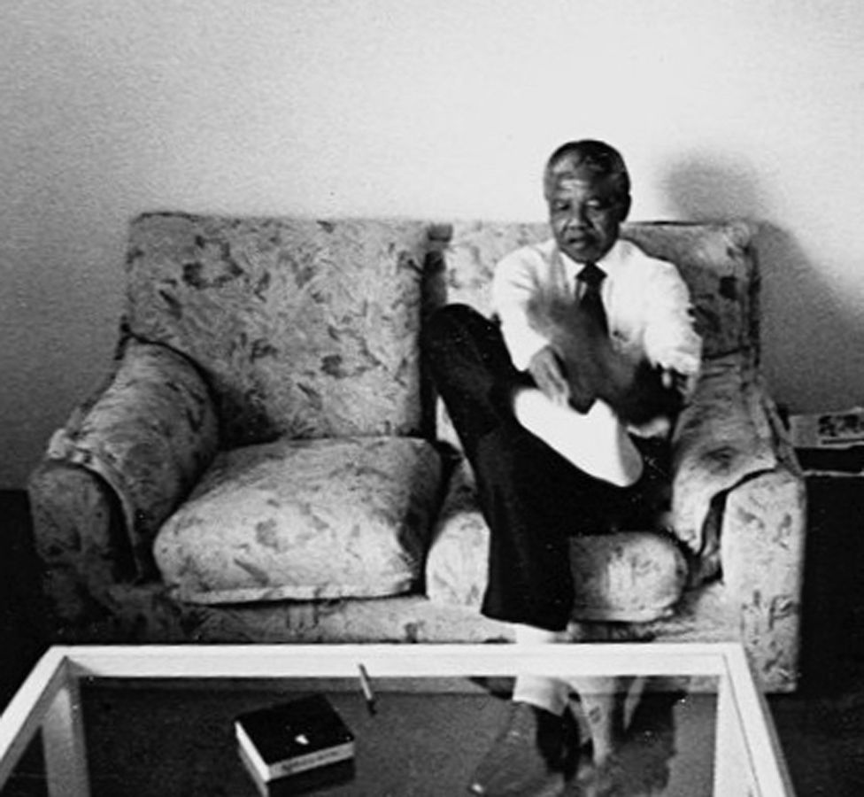 A photo by Sunmi Smart-Cole entitled: "Nelson Mandela at ease" - Kampala, Uganda, 1992, showing the antiapartheid leader taking off his socks