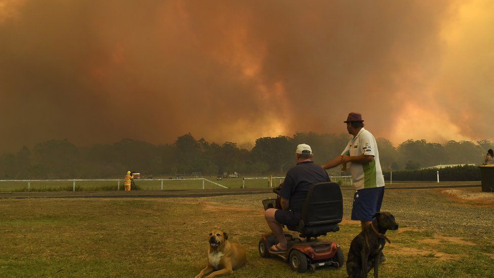 Locals watch as bushfires burn through farmland turning the skies above Nana Glen, 600km north of Sydney a smoky orange.