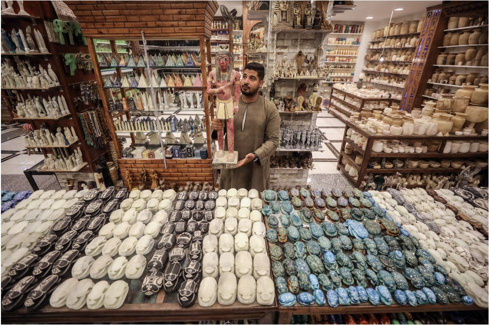 A man in a shop full of Egyptian handicraft.