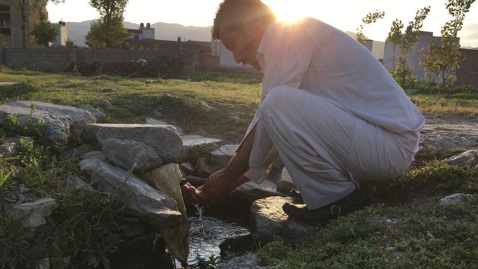A man washing hands at the well which was located inside the Bin Laden compound once - the compound has now been razed