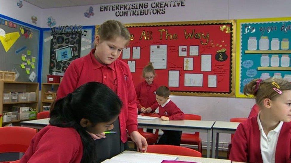 Pupils in a classroom with "Enterprising creative contributors" written on the wall
