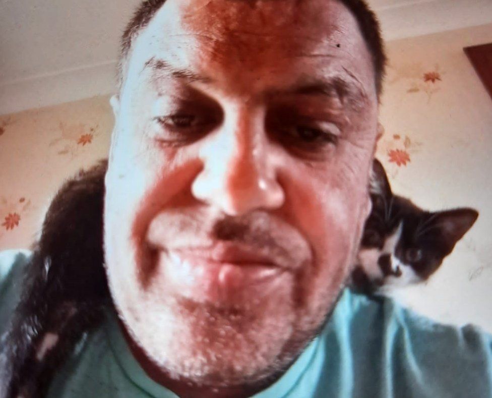 Philip Pakree with a cat sitting around his neck