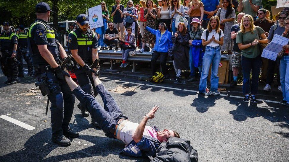 Oficerët e policisë largojnë një aktivist nga grupi protestues i Rebelimit të Zhdukjes në A12, gjatë demonstratës "XR kundërshton subvencionet fosile" në Hagë, Holandë, 27 maj 2023.