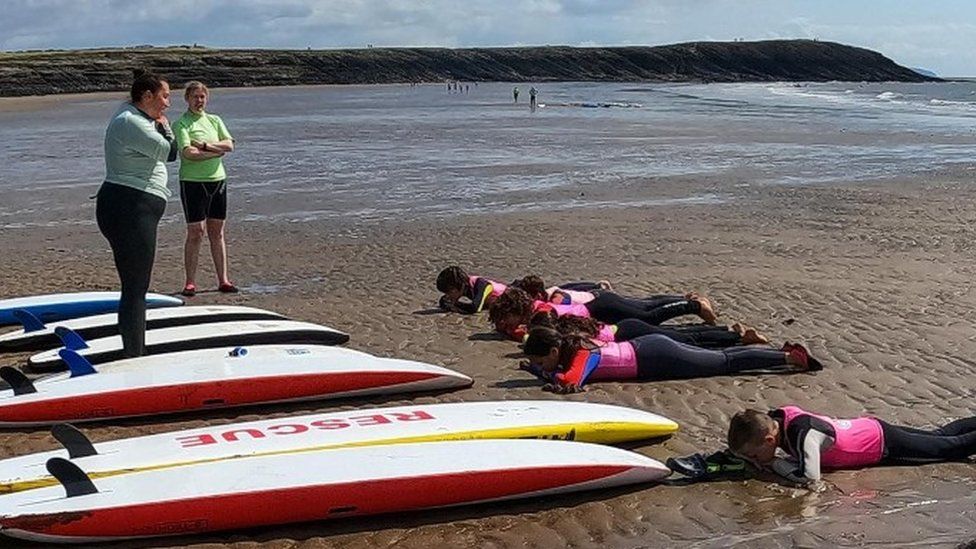 children, trainers and surfboards on beach