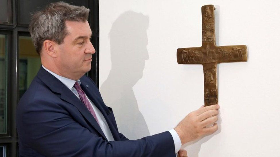 Bavaria's Premier Markus Söder places a cross in the lobby of the state chancellery in Munich