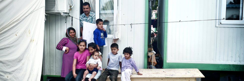 An Afghan family with six children stand outside their container on 11 May 2017 at Malakassa refugee camp in Greece