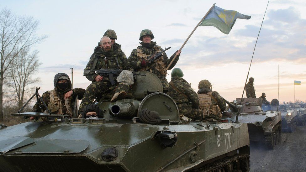 Ukrainian soldiers sit on top of a tank