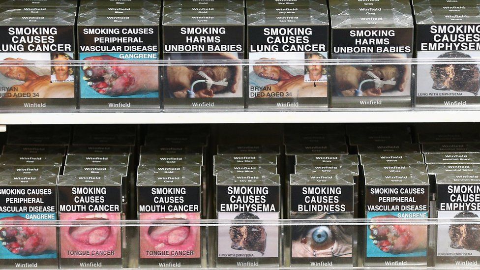 A display of plain packaged cigarette boxes featuring health warnings in a Sydney supermarket