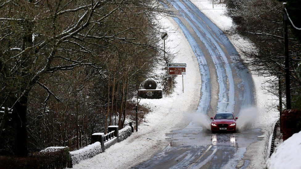 A car driving along a snowy road in Leek, Staffordshire
