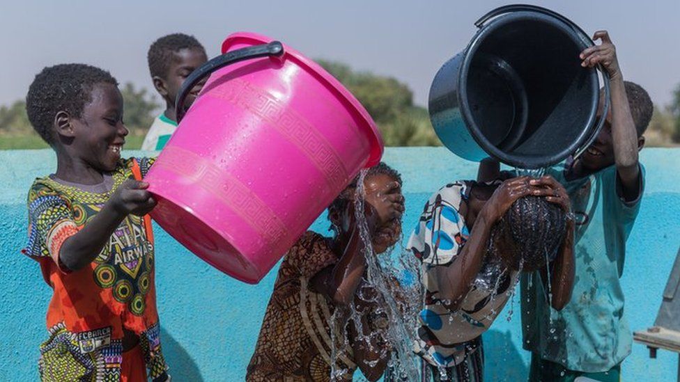 Children wash and play in clean water at a WaterAid pump