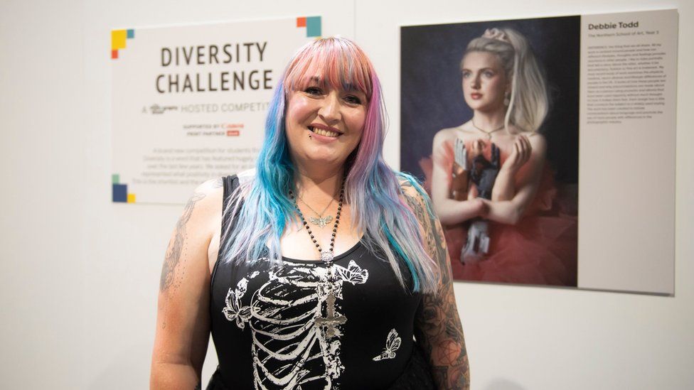 Woman with blue and purple hair smiles at the camera