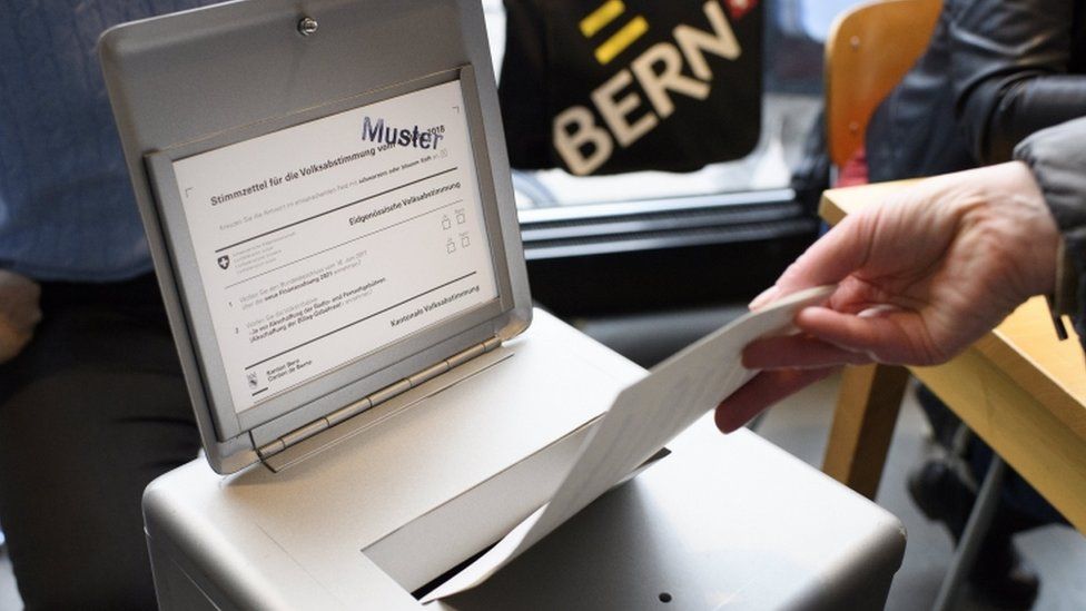 A person casts his ballot paper into the ballot box at a polling station in Berne, Switzerland,