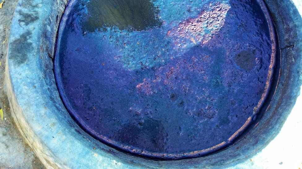 Close up of a dye pit filled with a murky indigo liquid
