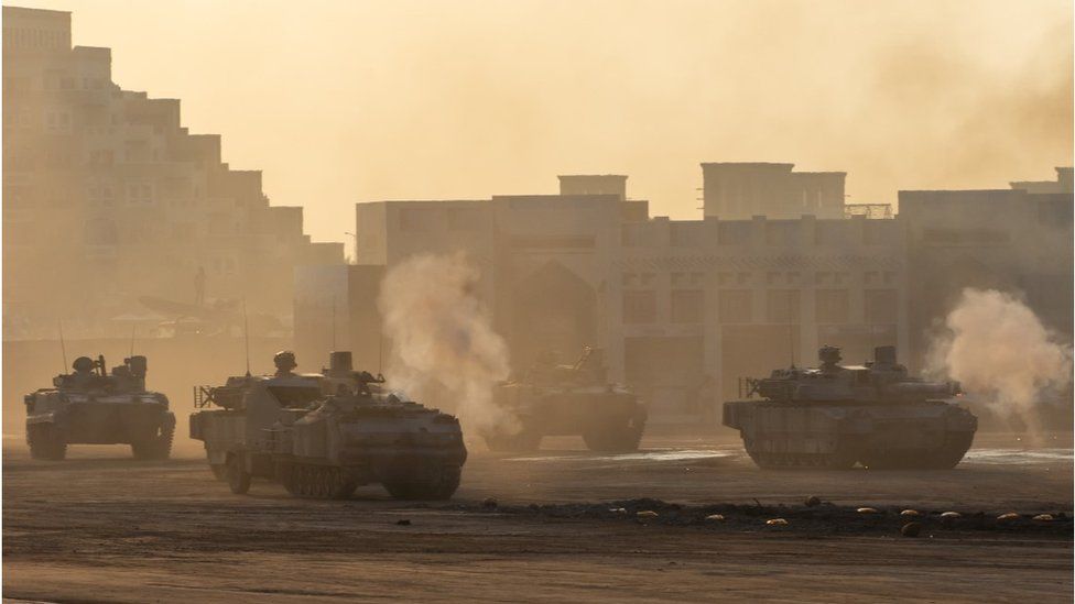 Series of Army tanks shooting and driving in an Afghan desert town