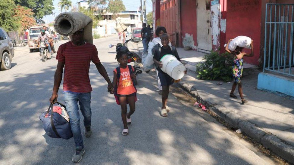 People fleeing from violence around their homes walk towards a shelter with their belongings, in Port-au-Prince, Haiti March 9, 2024.