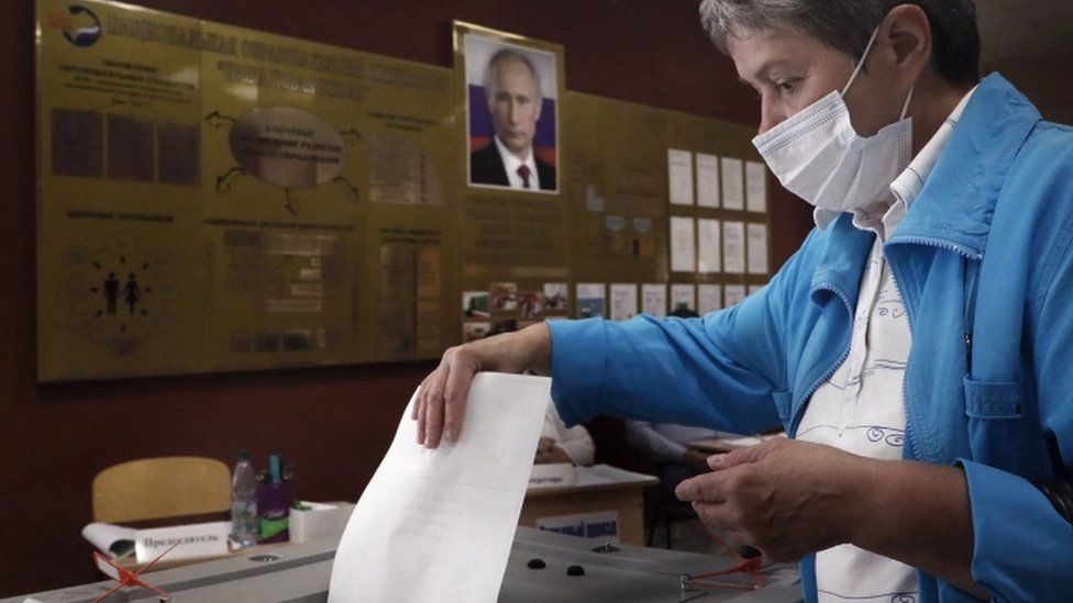 A woman voting in Russia's constitutional referendum under a poster of Vladimir Putin, June 2020