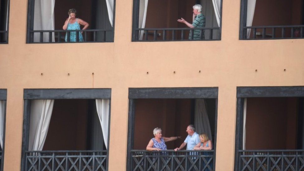 Tourists stand on the balcony of their rooms at the H10 Costa Adeje Palace Hotel in La Caleta, on February 25, 2020, where hundreds of people were confined to their rooms after an Italian tourist was hospitalised with a suspected case of coronavirus.