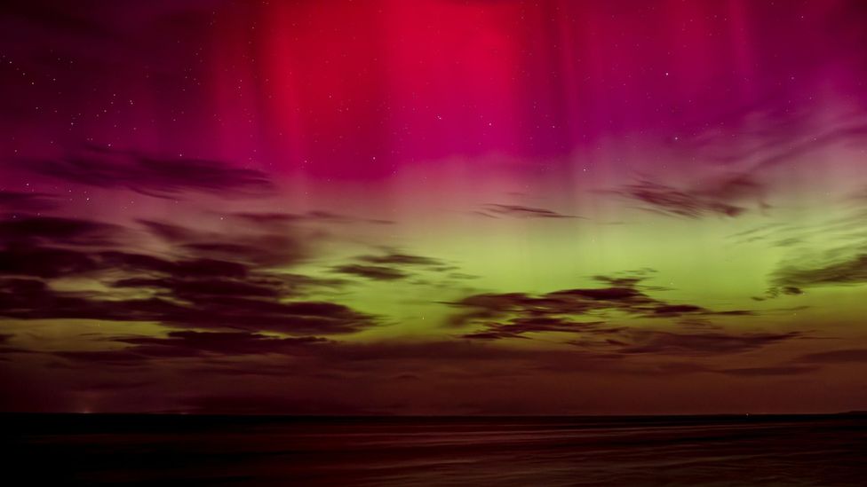 Pink and green Northern Lights above the sea