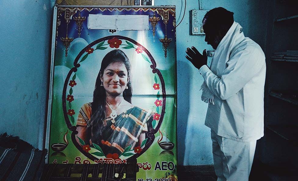 Mounika's father prays to a poster of her in her room