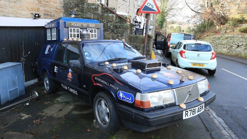 A replica Tardis attached to the top of a vehicle outside the couple's home
