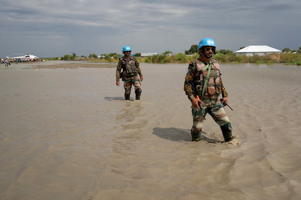 UN peacekeepers walk through water, after heavy rains and floods forced hundreds of thousands of people to leave their homes, in the town of Pibor