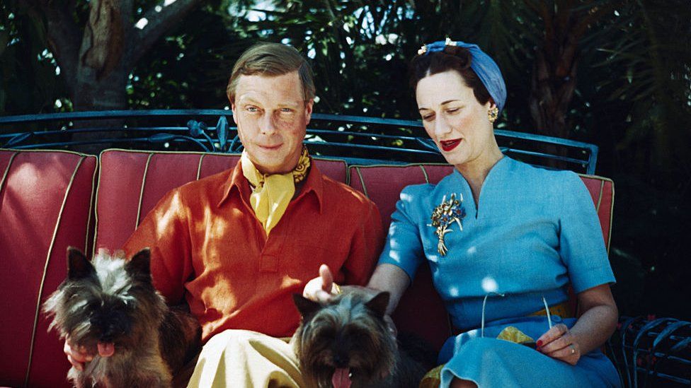 The Duke and Duchess of Windsor seated outdoors with two small dogs.