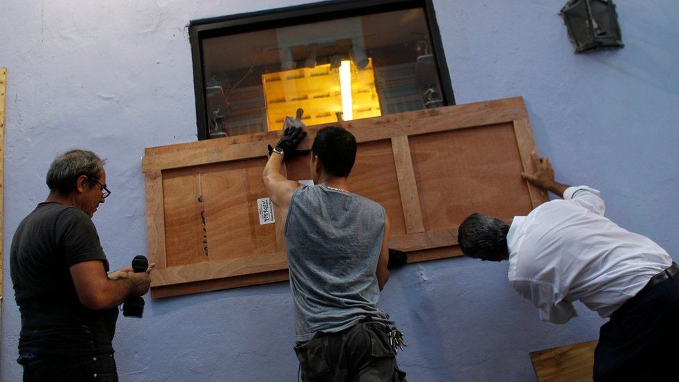 Image shows people boarding up the windows of a business in preparation for Hurricane Maria in San Juan, Puerto Rico on 18 September 2017
