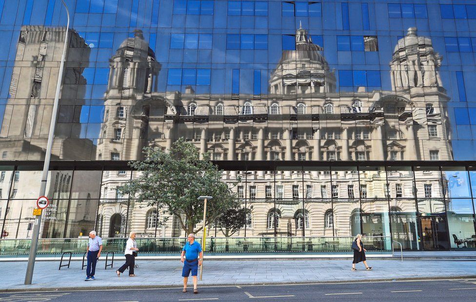 A reflection of the Port of Liverpool Building under blue skies seen in a glass building