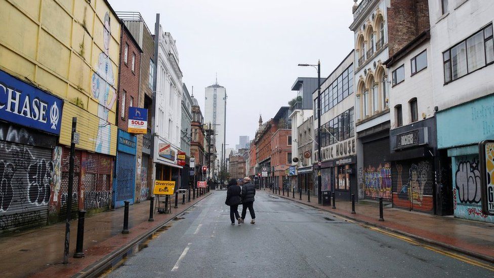 Люди идут по пустой улице Манчестера
