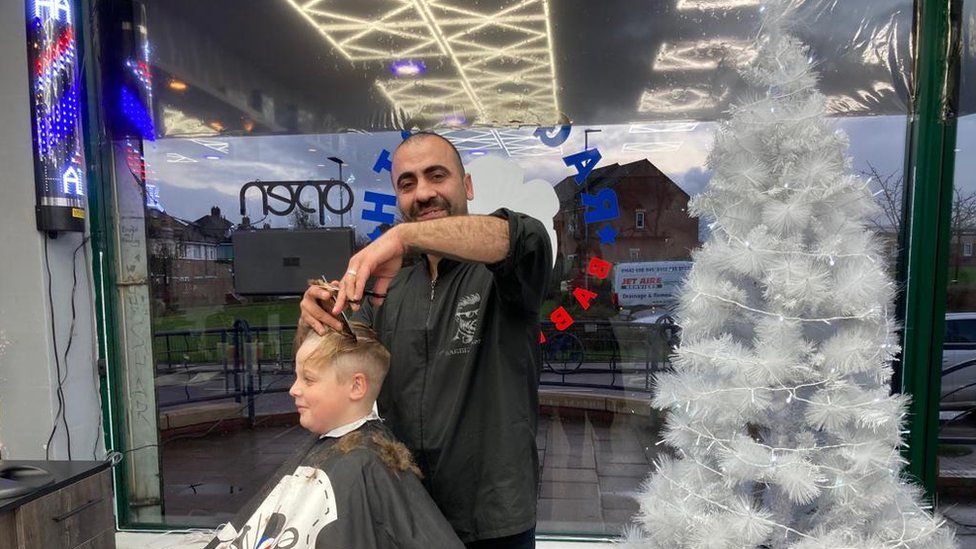 Mohammed Niromande cutting the hair of a young customer
