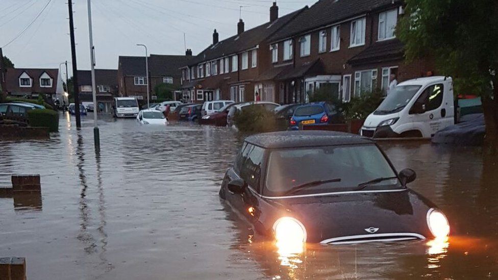 A Mini driver tries to drive its way out of a flooding in Romford, Greater London