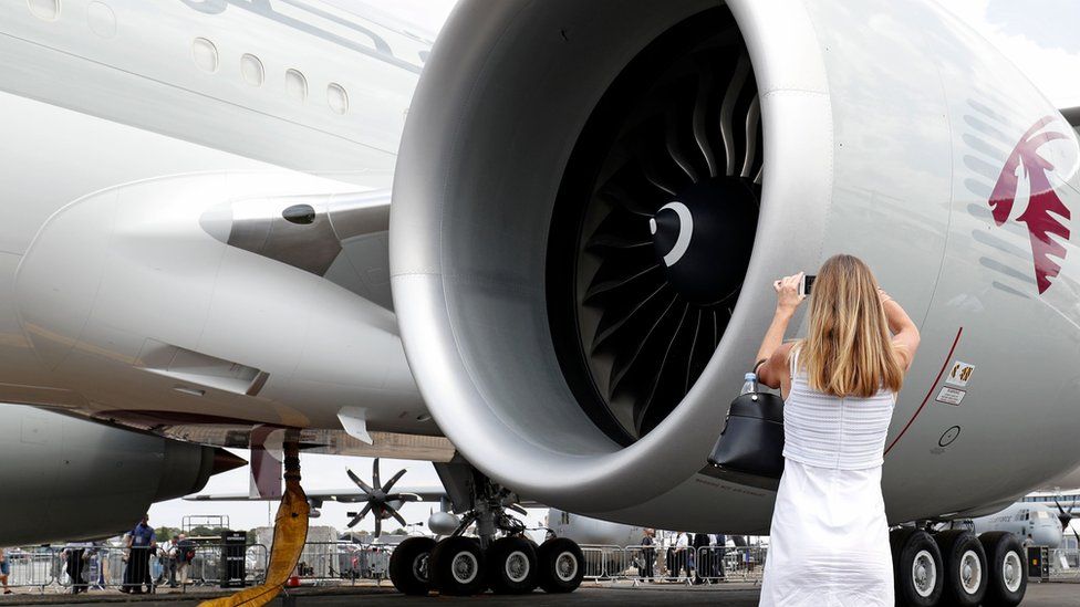A woman photographs a GE engine inside Qatar Airways aeroplane