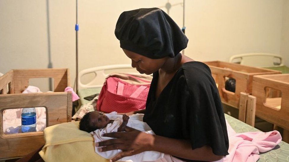 A woman holds a malnourished baby