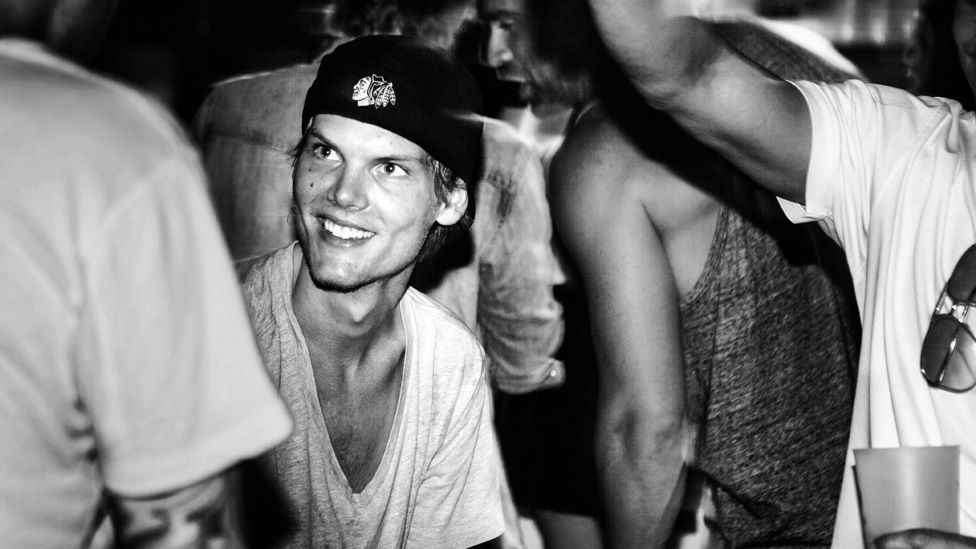 Avicii surrounded by people, apparently in a nightclub