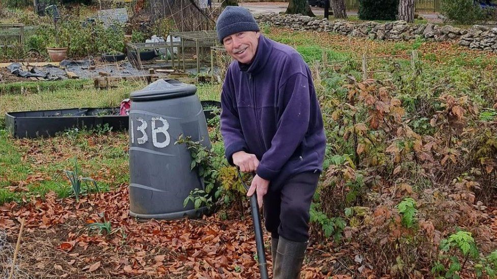 Man smiling whilst digging at allotment plot