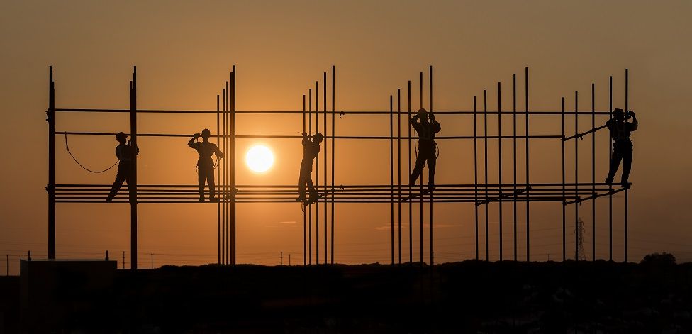 Workers working on scaffolding during sunset