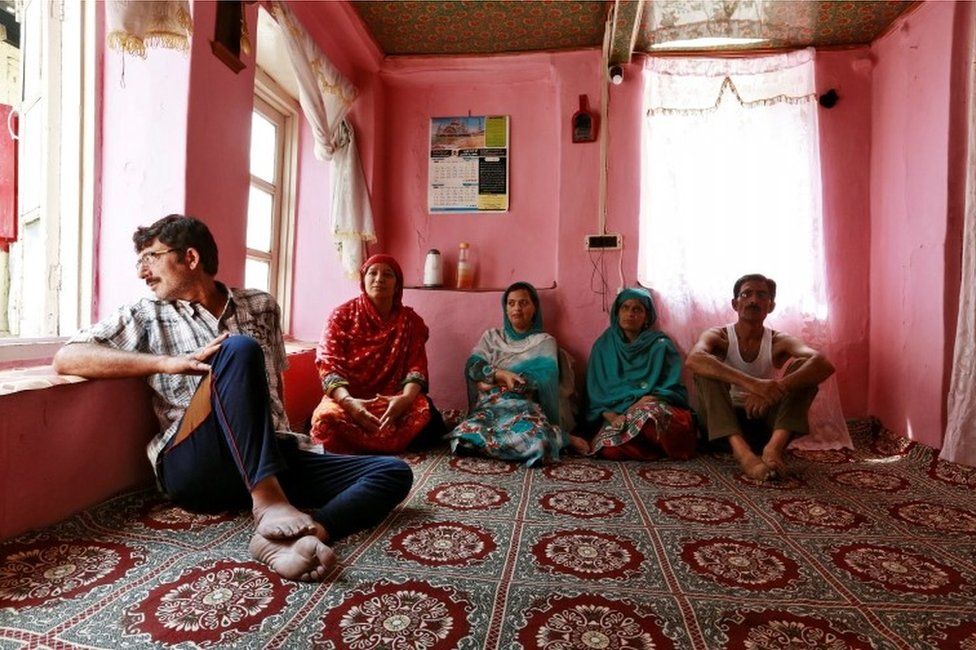 Members of a family watch television in their home in Srinagar as the city remains under curfew following weeks of violence in Kashmir, August 21, 2016.