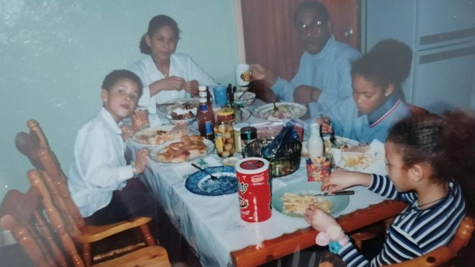 Ogogo as a child with his family eating at a table