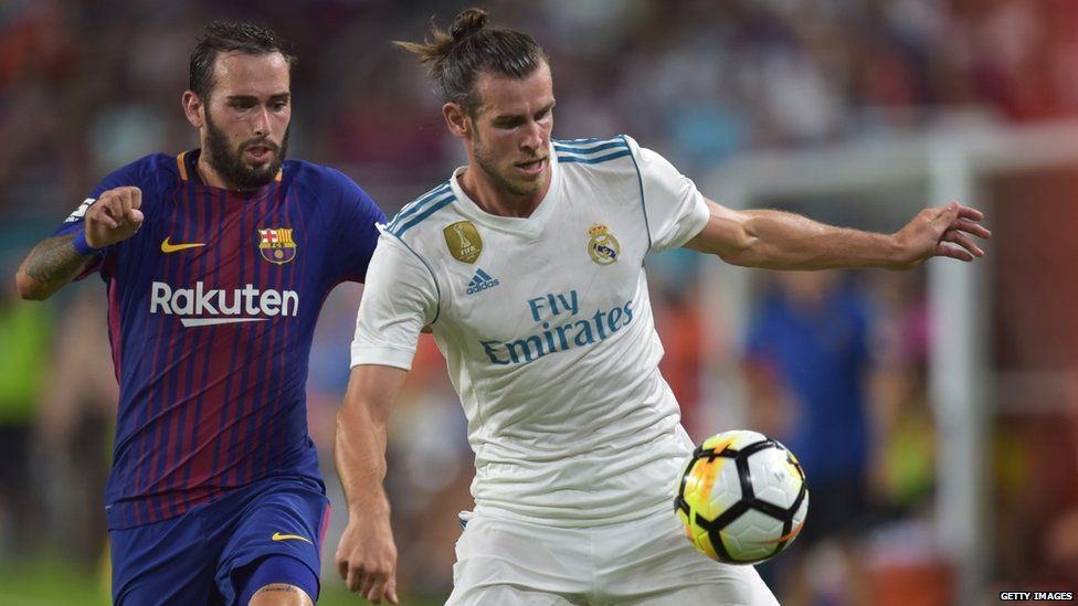 Gareth Bale of Real Madrid is challenged by Arda Turan of Barcelona
