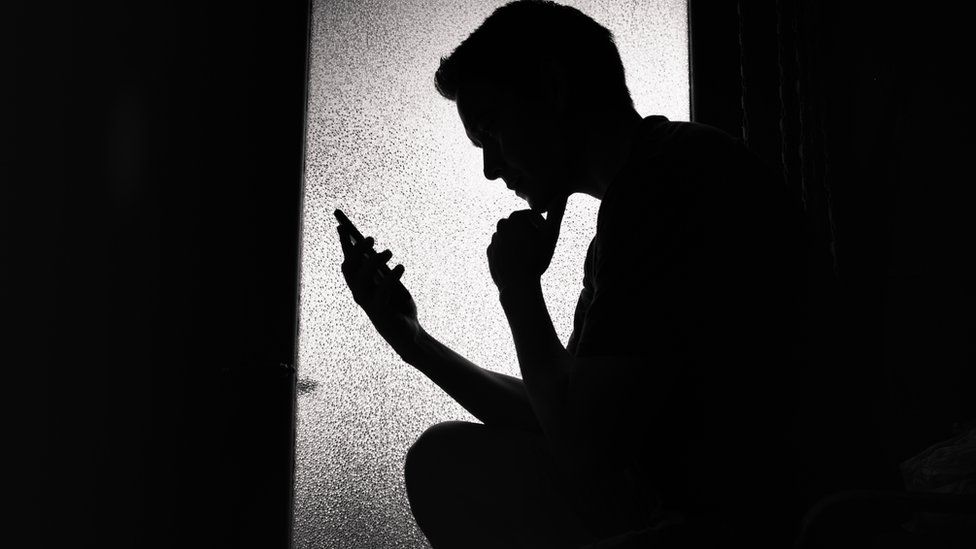 Stock image of teenager with phone in silhouette