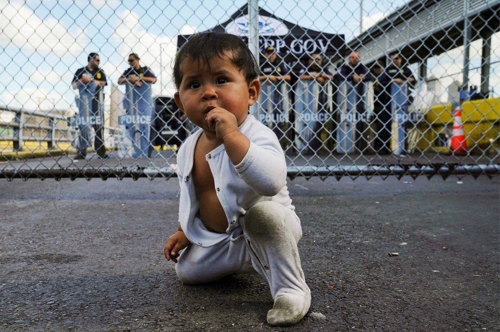 A baby in front of the gates to the Gateway International Bridge in Matamoros, Mexico